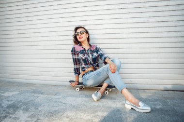 Genç esmer kız açık havada kaykay ile poz