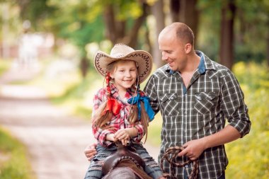 Kovboy şapkası binme midilli küçük kız babasıyla Park