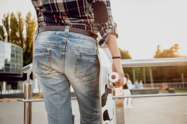 Güzel dalgalı saçlı öpebileceğinize kız açık havada kaykay ile poz Kareli gömlekli