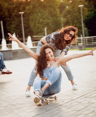 İki genç karışık yarış kız rahat kıyafetler ile kaykay sokakları etrafında yürüyüş içinde