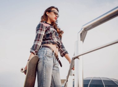 Genç esmer kız açık havada kaykay ile poz