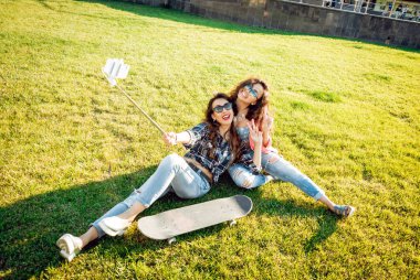 İki genç karışık yarış kız rahat kıyafetler selfie yeşil çim üzerinde yapıyor