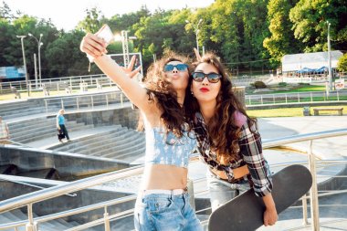 İki genç karışık yarış kız açık havada kaykay ile selfie yapıyor
