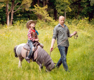 Kovboy şapkası binme midilli küçük kız babasıyla Park