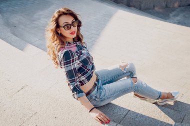 Güzel dalgalı saçlı öpebileceğinize kız açık havada kaykay ile poz Kareli gömlekli