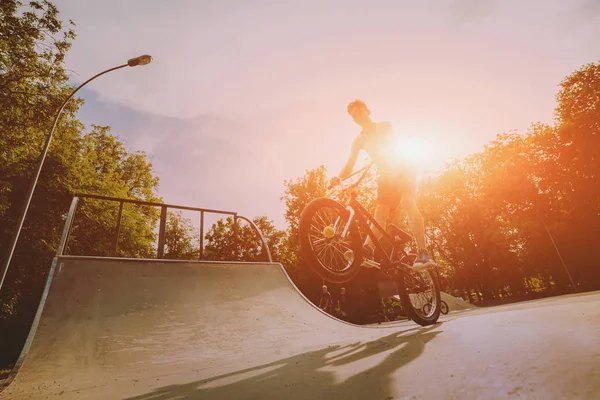 Teenager riding a BMX in skate park.