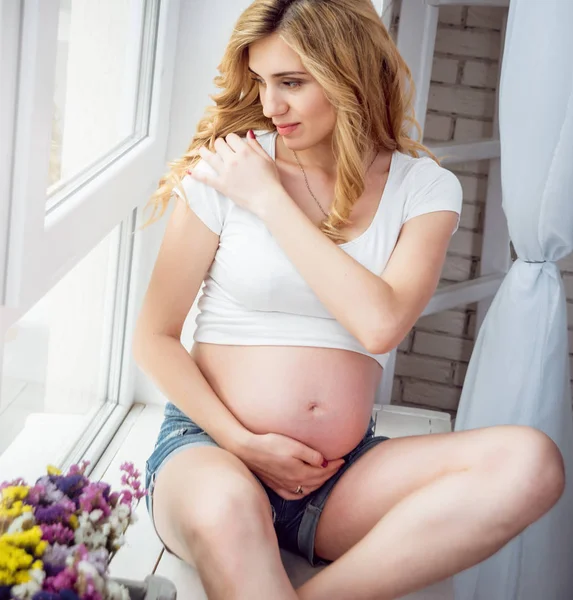 在窗口附近的年轻怀孕的妇女 — 图库照片