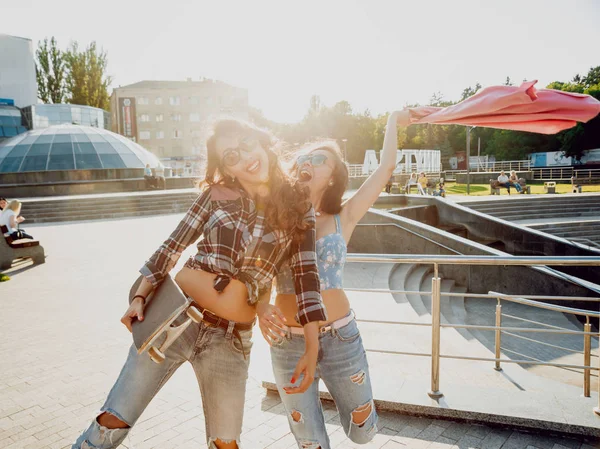 İki genç karışık yarış kız rahat kıyafetler ile kaykay sokakları etrafında yürüyüş içinde