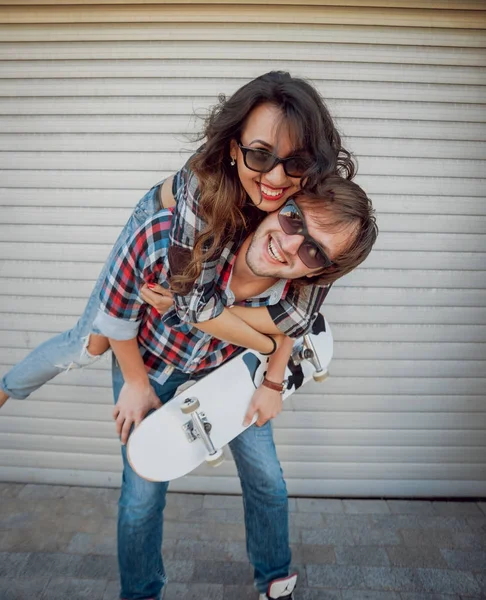 Jovem Casal Com Skate Contra Portões Rolantes — Fotografia de Stock