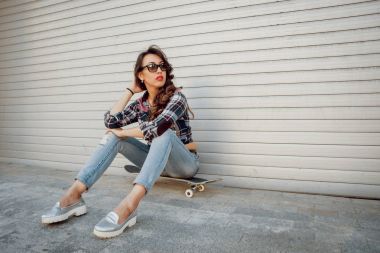 Genç esmer kız açık havada kaykay ile poz