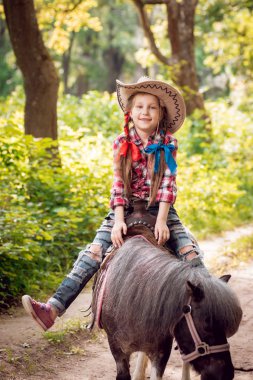 Park midilli sürme kovboy şapkalı örgü ile küçük kız