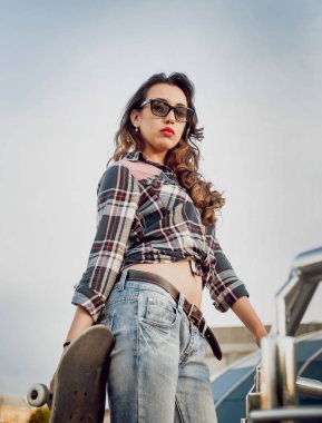 Güzel dalgalı saçlı öpebileceğinize kız açık havada kaykay ile poz Kareli gömlekli