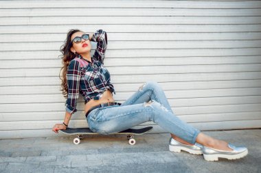 Genç esmer kız açık havada kaykay ile poz