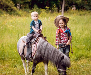 Küçük kız ve at binme erkek kardeşi yeşil park midilli