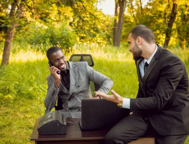 İki genç çok kültürlü iş adamları iş park yerinde. Uzak iş kavramı.