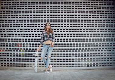 Genç esmer kız açık havada kaykay ile poz