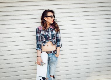 Genç esmer kız açık havada kaykay ile poz