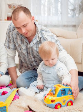 Baba evde oğluyla oynuyor.