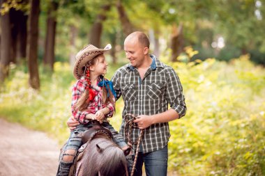 Kovboy şapkası binme midilli küçük kız babasıyla Park