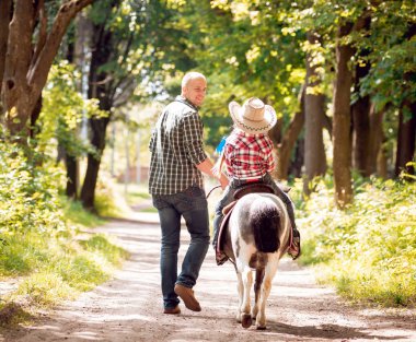 Kovboy şapkası binme midilli küçük kız babasıyla Park