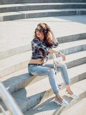 Genç esmer kız açık havada kaykay ile poz