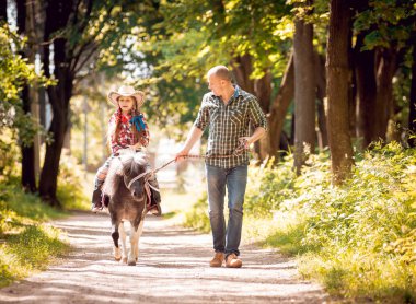 Kovboy şapkası binme midilli küçük kız babasıyla Park
