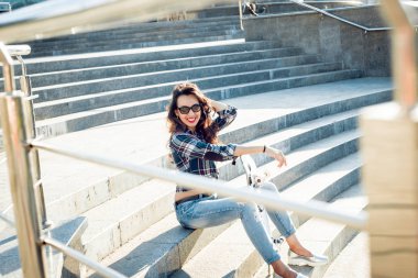 Genç esmer kız açık havada kaykay ile poz