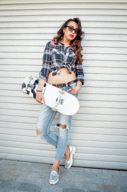 Güzel dalgalı saçlı öpebileceğinize kız açık havada kaykay ile poz Kareli gömlekli