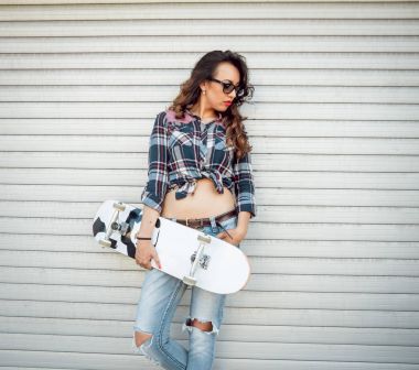 Genç esmer kız açık havada kaykay ile poz