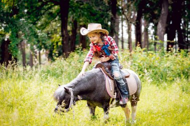 Park midilli sürme kovboy şapkalı örgü ile küçük kız