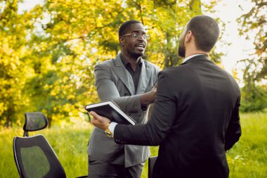 İki genç çok kültürlü iş adamları iş park yerinde. Uzak iş kavramı.
