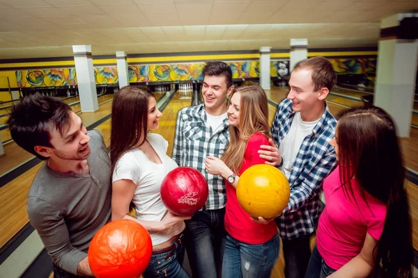 Cheerful friends at the bowling alley with balls