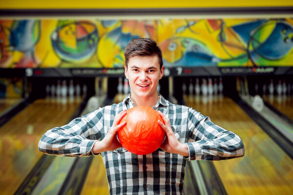 Happy young man at the bowling alley with ball