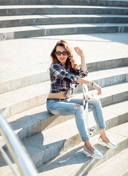 Genç esmer kız açık havada kaykay ile poz