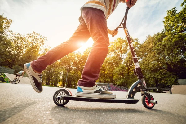 男孩在公园里骑着一辆脚踏滑板车 美丽的背景 — 图库照片