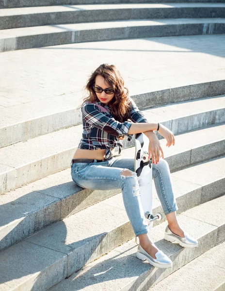 Genç esmer kız açık havada kaykay ile poz