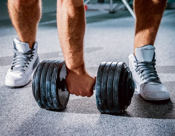 Low angle of hand with dumbbell on floor