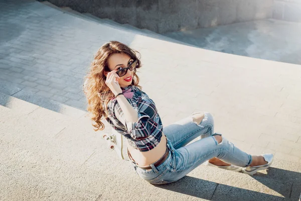 Genç esmer kız açık havada kaykay ile poz