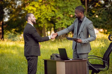 İki genç çok kültürlü iş adamları iş park yerinde. Uzak iş kavramı.