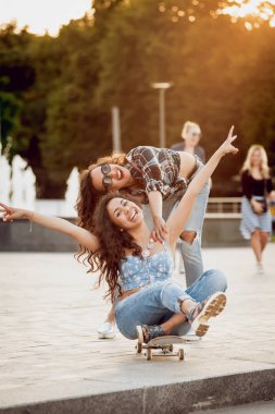 İki genç kız açık havada kaykay ile eğleniyor