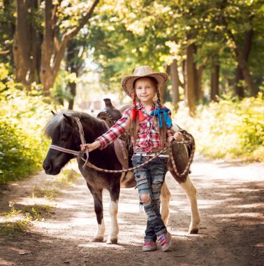 Park midilli sürme kovboy şapkalı örgü ile küçük kız