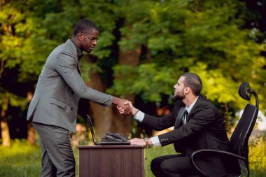 İki genç çok kültürlü iş adamları iş park yerinde. Uzak iş kavramı.