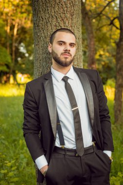 Park ağaç yakınındaki kravat ile siyah elbiseli adam genç sakallı