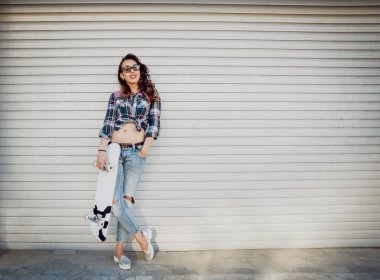 Genç esmer kız açık havada kaykay ile poz