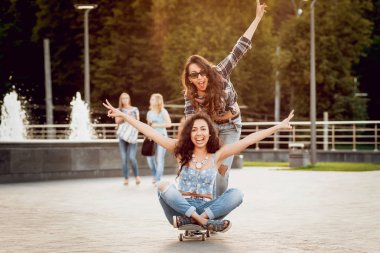 Kaykay posig şehir ve having fun çevresinde iki genç kızla