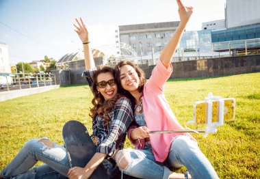 İki genç karışık yarış kız rahat kıyafetler selfie yeşil çim üzerinde yapıyor