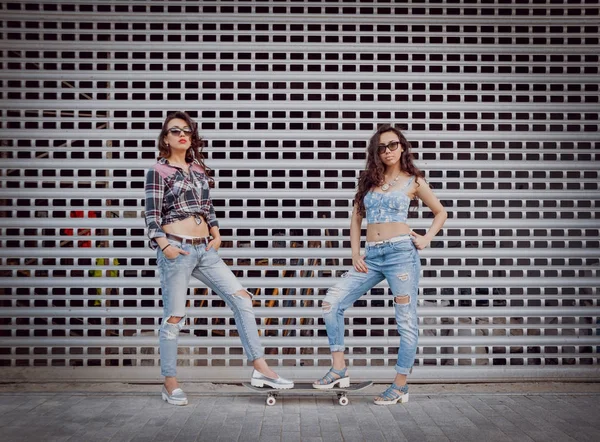 Kaykay posig şehir ve having fun çevresinde iki genç kızla