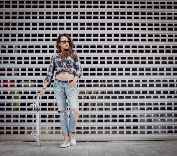 Güzel dalgalı saçlı öpebileceğinize kız açık havada kaykay ile poz Kareli gömlekli