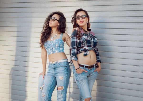 İki genç karışık yarış kız rahat kıyafetler ile kaykay sokakları etrafında yürüyüş içinde