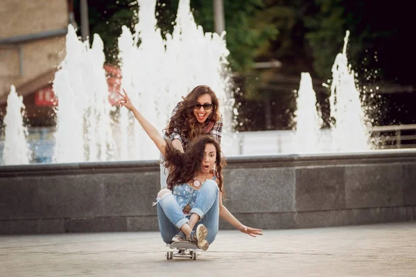 İki genç kız açık havada kaykay ile eğleniyor